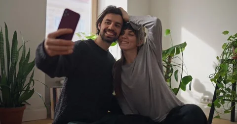 Happy guy hugging his girlfriend and taking selfie with her during cozy time and Stock Footage 318079847