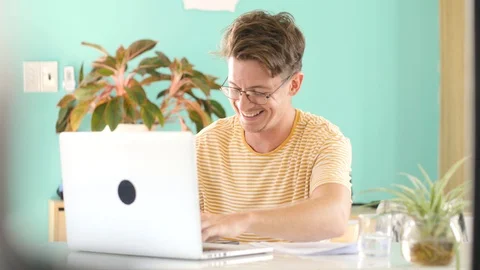 A happy guy laughing hard while working studying at home in front of the laptop. Stock Footage 128719913