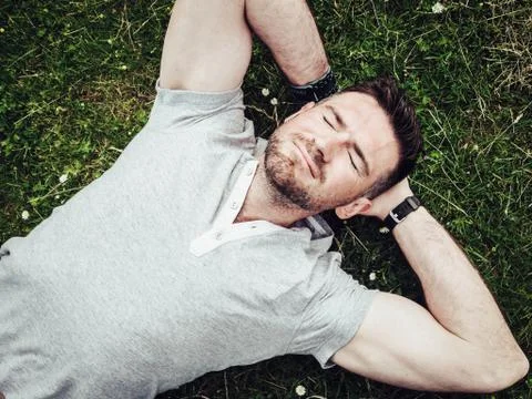 Happy guy lying on the green grass Stock Photos