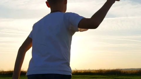 Happy guy playing with a paper airplane in a field in the sun. Silhouette at Stock Footage 80388784