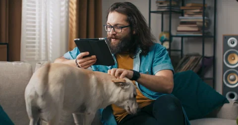 Happy guy relaxes on couch with tablet in hand, browsing social media websites Stock Footage 218201047