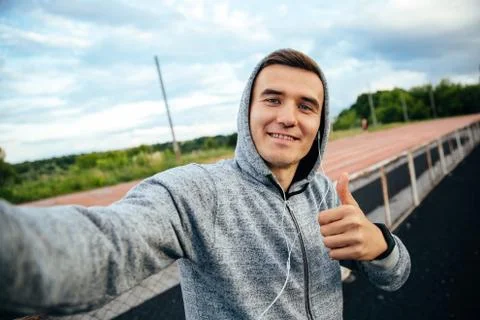 Happy guy showing a thumb while taking a selfie on smartphone Stock Photos