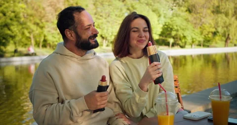 Happy guy with stubble and his girlfriend sit at a table in a cafe and eat a hot Stock Footage 280628876