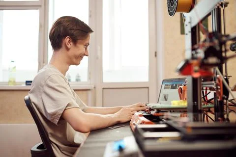 Happy guy using netbook near 3D printers Stock Photos