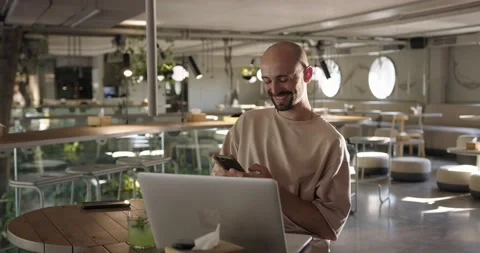 Happy guy using smartphone and laptop at cafe Stock Footage 159082605