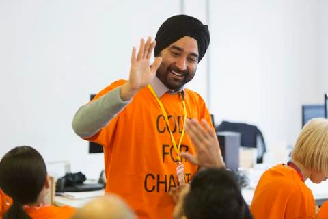 Happy hackers high-fiving, coding for charity at hackathon Stock Photos