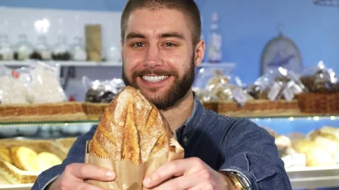 Happy handsome bearded man posing with freshly baked bread Stock Footage 84760876