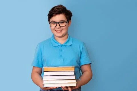 A happy handsome boy, dark-haired, wearing glasses and a blue T-shirt, holding a Stock Photos