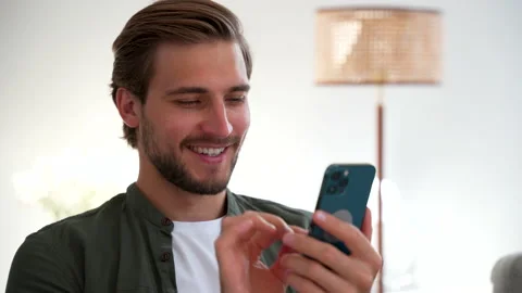 Happy Handsome Caucasian Man Using Smartphone at Home, Browsing the Internet Stock Footage 220864396