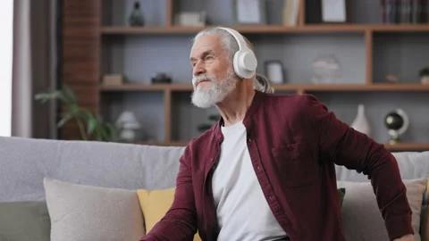 Happy handsome elderly gray-haired man in white headphones enjoy listening Stock Footage 219644926