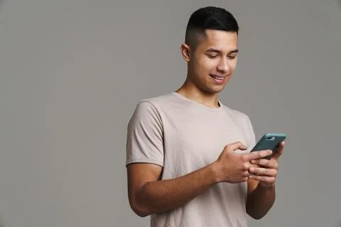 Happy handsome guy using mobile phone and smiling Stock Photos