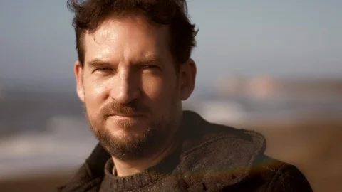 Happy handsome man with beard smiling in front of the ocean slow motion at su Stock Footage 107833922