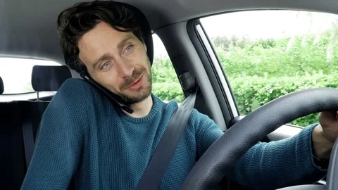 Happy handsome man in car driving and talking on the phone with girlfriend Stock Footage 74753136