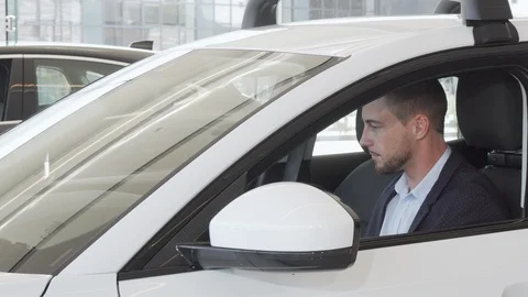 Happy handsome man examining interior of a new car sitting inside Stock-Footage 115583818