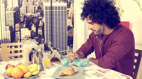 Happy handsome man at home having breakfast listening music Stock Footage 49966320