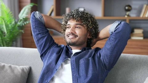 Happy handsome man relaxing while sitting on cozy sofa in living room at home.  Stock Footage 296762201