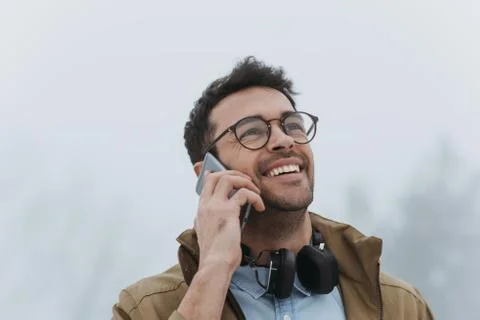 Happy handsome man smiling while having conversation on smartphone with his f Stock Photos