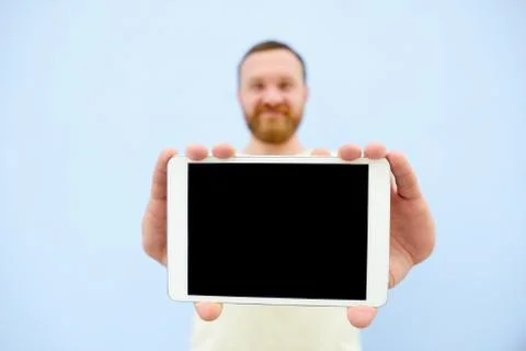 Happy Handsome young man with a beard showing something on a tablet isolated  Stock Photos