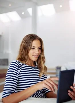 Happy with her progress so far. an attractive young woman using a digital tablet Stock Photos