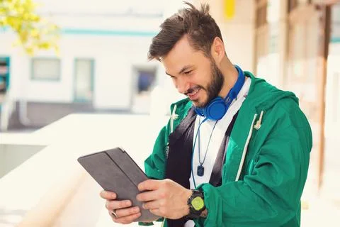 Happy hipster guy using his laptop while standing outdoors on a sunny day Stock Photos