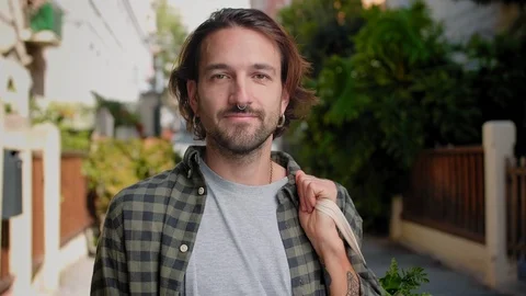 Happy Hispanic beard man holding Eco bag full of greenery and smiling at cosy Stock Footage 111071008