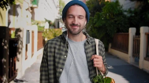 Happy Hispanic guy standing at small street and listening joy music using white Stock Footage 111071373