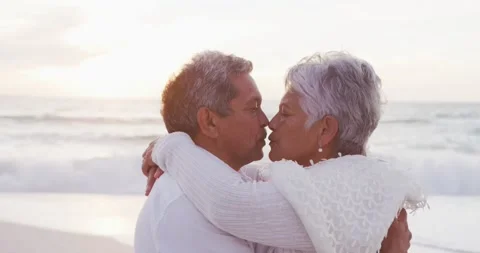 Happy hispanic just married senior couple kissing on beach at sunset Stock Footage 338433721