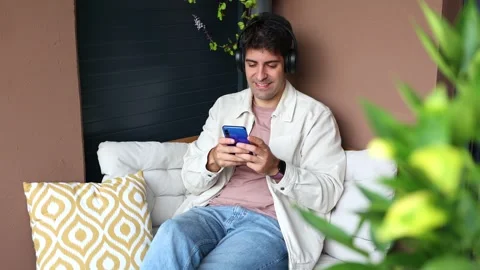 Happy hispanic man with headphones using smartphone Stock Footage 319027694