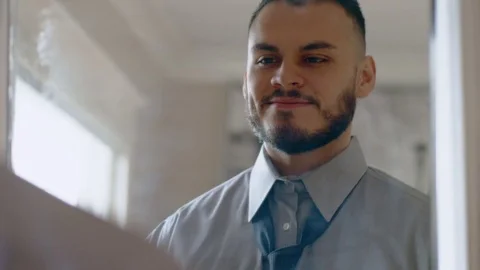 Happy hispanic man tying tie getting ready in mirror Stock Footage 84483596