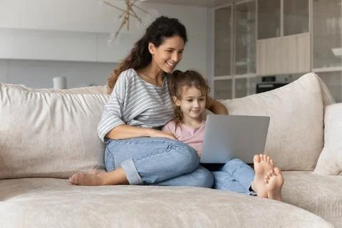 Happy Hispanic mom and little daughter use laptop Stock Photos