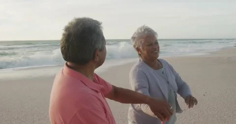 Happy hispanic senior couple dancing on beach at sunset Stock Footage 336436008