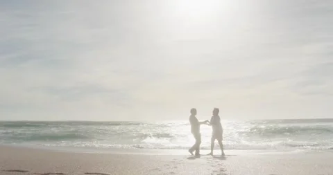Happy hispanic senior couple dancing on beach at sunset Stock Footage 339412486