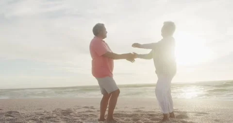 Happy hispanic senior couple dancing on beach at sunset Stock Footage 339589417