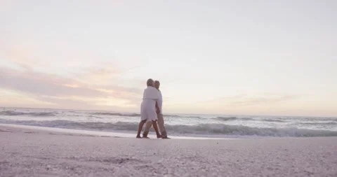 Happy hispanic senior couple walking on beach at sunset Stock Footage 337536571