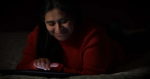 Happy Hispanic Woman Using Electronic Tablet in Dark Environment Lit by Tablet Stock Footage 102928894