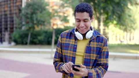 Happy hispanic young man using phone in the street Video stock 258326258