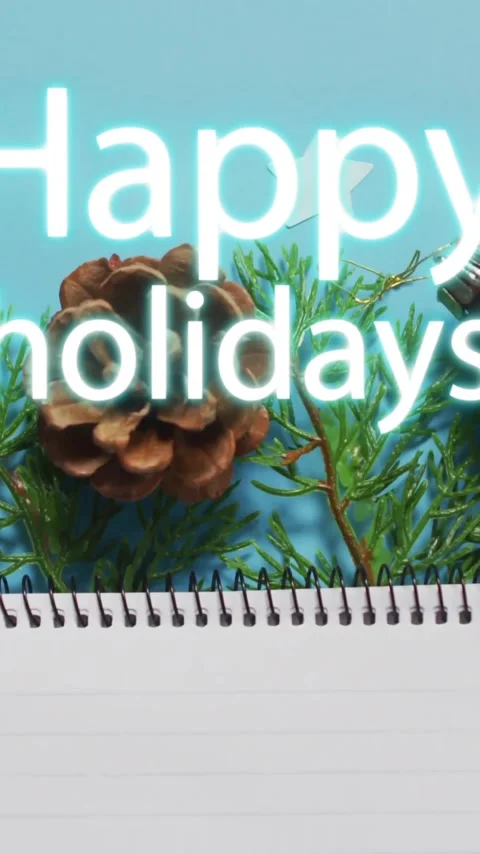 Happy holidays text animation over Christmas decorations and blank notepad Video stock 343739682