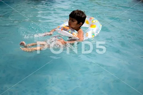 Happy Indian boy swimming in a pool, Kid wearing swimming costume along ...