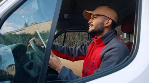 Happy indian courier using tablet in the van Stock Photos