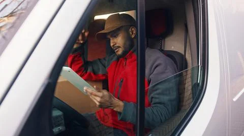 Happy indian courier using tablet in the van Stock Photos