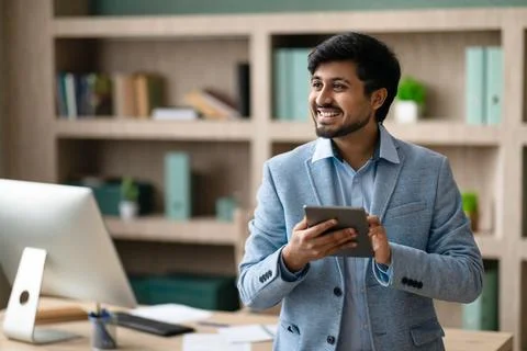Happy Indian programmer man using tablet standing in modern office Stock Photos