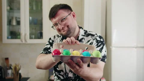 Happy individual presenting pastel Easter eggs in cozy kitchen Video stock 330497660