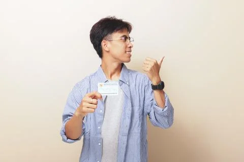 Happy Indonesian guy smiling while holding Indonesian identity card or KTP .. Stock Photos