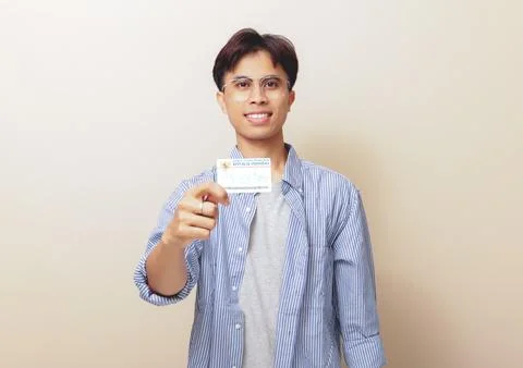 Happy Indonesian guy smiling while holding Indonesian identity card or KTP .. Stock Photos