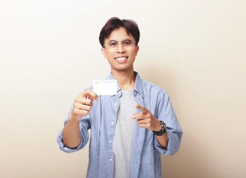 Happy Indonesian guy smiling while holding Indonesian identity card or KTP .. Stock Photos