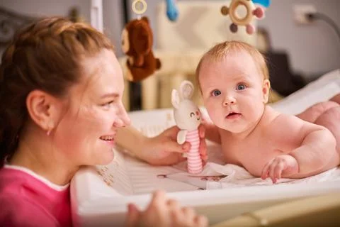 Happy interaction on changing table in cozy nursery Stock Photos
