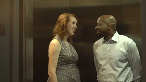 A happy interracial couple get into an elevator, chatting Stock Footage 44236949