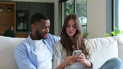 Happy interracial couple using smartphone together Stock Footage 334636366