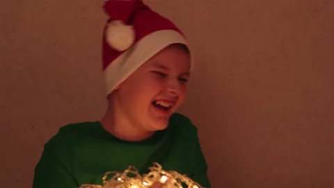 Happy, joyful boy in a red cap laughs a lot while playing with New Year's Stock Footage 165327922