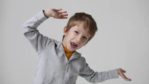 Happy joyful child having fun rejoicing at victory indoors on gray background Stock Footage 168907390
